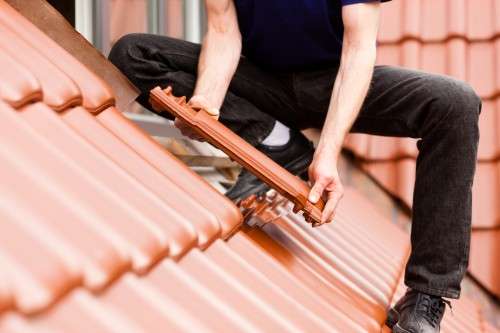 A man is putting tile down on a roof