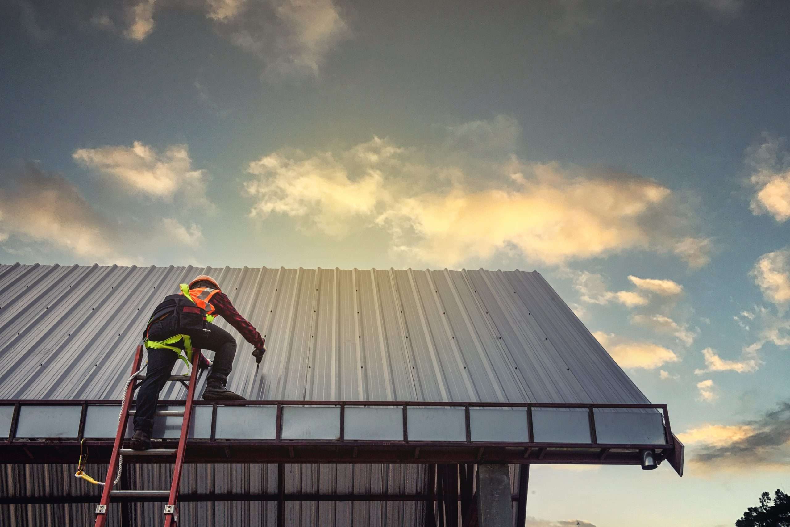 Worker man building tradesman on the roof of a house with safety helmet